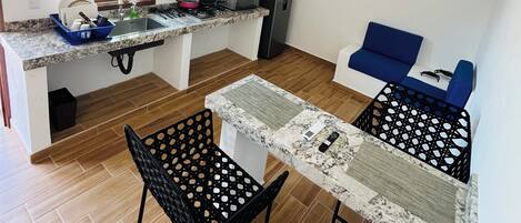 A compact kitchen with a window, a ceiling fan, and a dining area with two chairs.