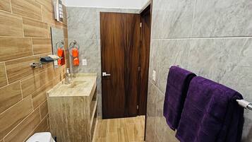 Een badkamer met toilet, wastafel en een houten deur.