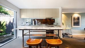 Una cocina moderna con una isla grande, taburetes de madera y vistas al exterior.