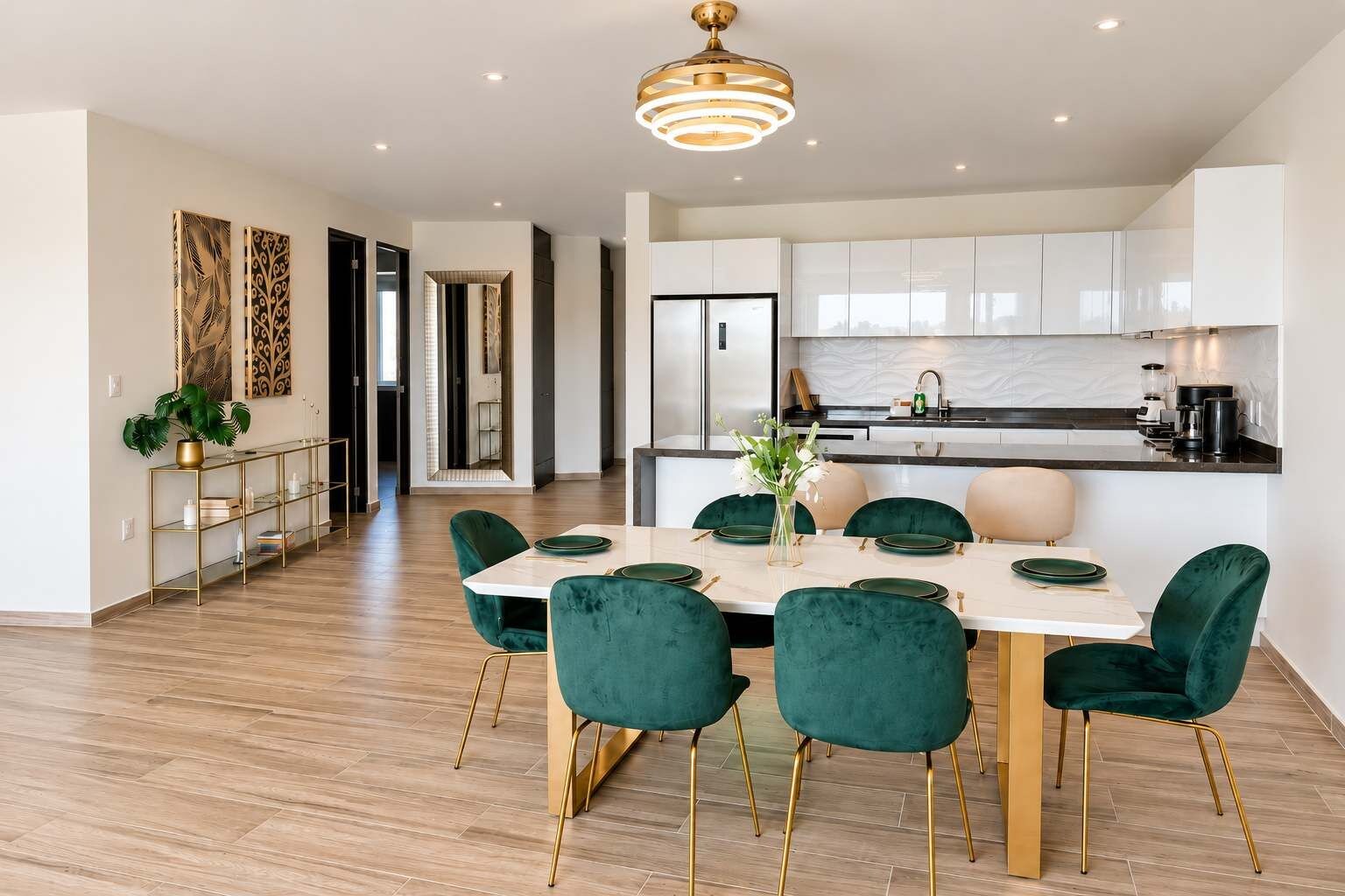 Una cocina moderna con armarios blancos, un refrigerador de acero inoxidable y una zona de comedor con una mesa blanca y sillas verdes.