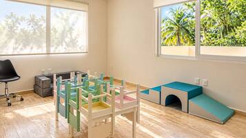 Habitación con área de juegos, escritorio y ventana con vista a la vegetación.