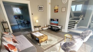 A living room with a sofa, coffee table, TV, and a staircase leading to another level. - Spacious house near White Water Walk and many attractions (Niagara Falls)