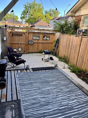 A backyard with a wooden deck, a grill, two lounge chairs, and a wooden fence. - Spacious house near White Water Walk and many attractions (Niagara Falls)