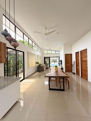 A spacious interior with a dining area, a ceiling fan, and large windows allowing natural light. - Exclusive Villa with Pool in Bahía Ballena (Osa)