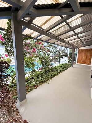 A covered outdoor area with a concrete floor, metal beams, and a view of a pool. - Exclusive Villa with Pool in Bahía Ballena (Osa)