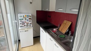 Angolo cottura funzionale con frigorifero, lavello e tagliere in legno.