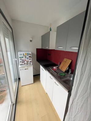 Eine kleine Küche mit Kühlschrank, Spüle und Schneidebrett.