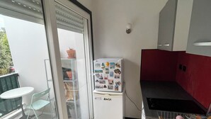 Una cucina compatta con frigorifero, lavello e zona pranzo con tavolo e sedie.