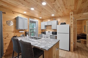 Eine kleine Küche mit Holzwänden, einer Granit Arbeitsplatte und modernen Geräten.