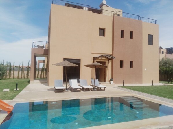 A modern building with a pool, lounge chairs, and umbrellas. - Exceptional villa with private pool and 1300m² grounds (Marrakech)