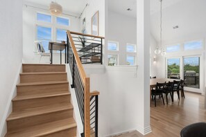 Una escalera de madera con barandillas negras que conduce a un comedor con mesa y sillas.