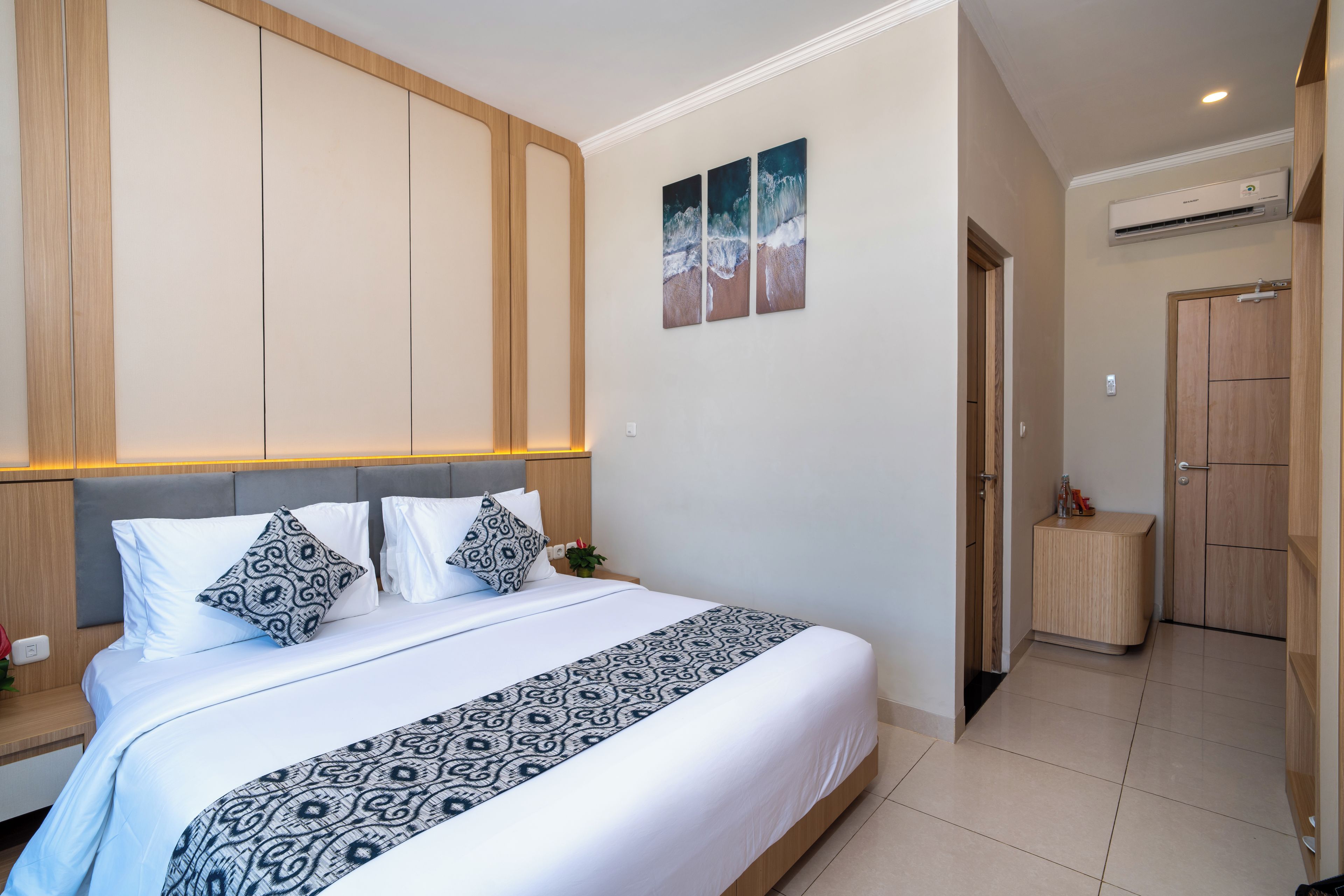 A modern bedroom with a large bed, a headboard, a bedside table, a nightstand, and a small bedside table with a lamp.
