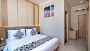 A modern bedroom with a large bed, a headboard, a bedside table, a nightstand, and a small bedside table with a lamp.