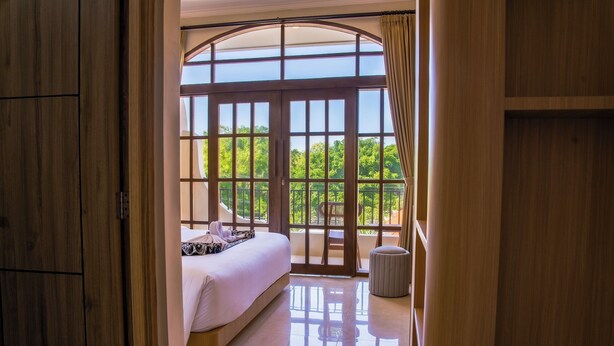 A bedroom with a large bed, a view through a glass door, and a balcony. - Sandat Mas Uluwatu (Uluwatu)
