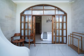 A room with a bed, a chair, a small table, and a wooden bench. - Sandat Mas Uluwatu (Uluwatu)