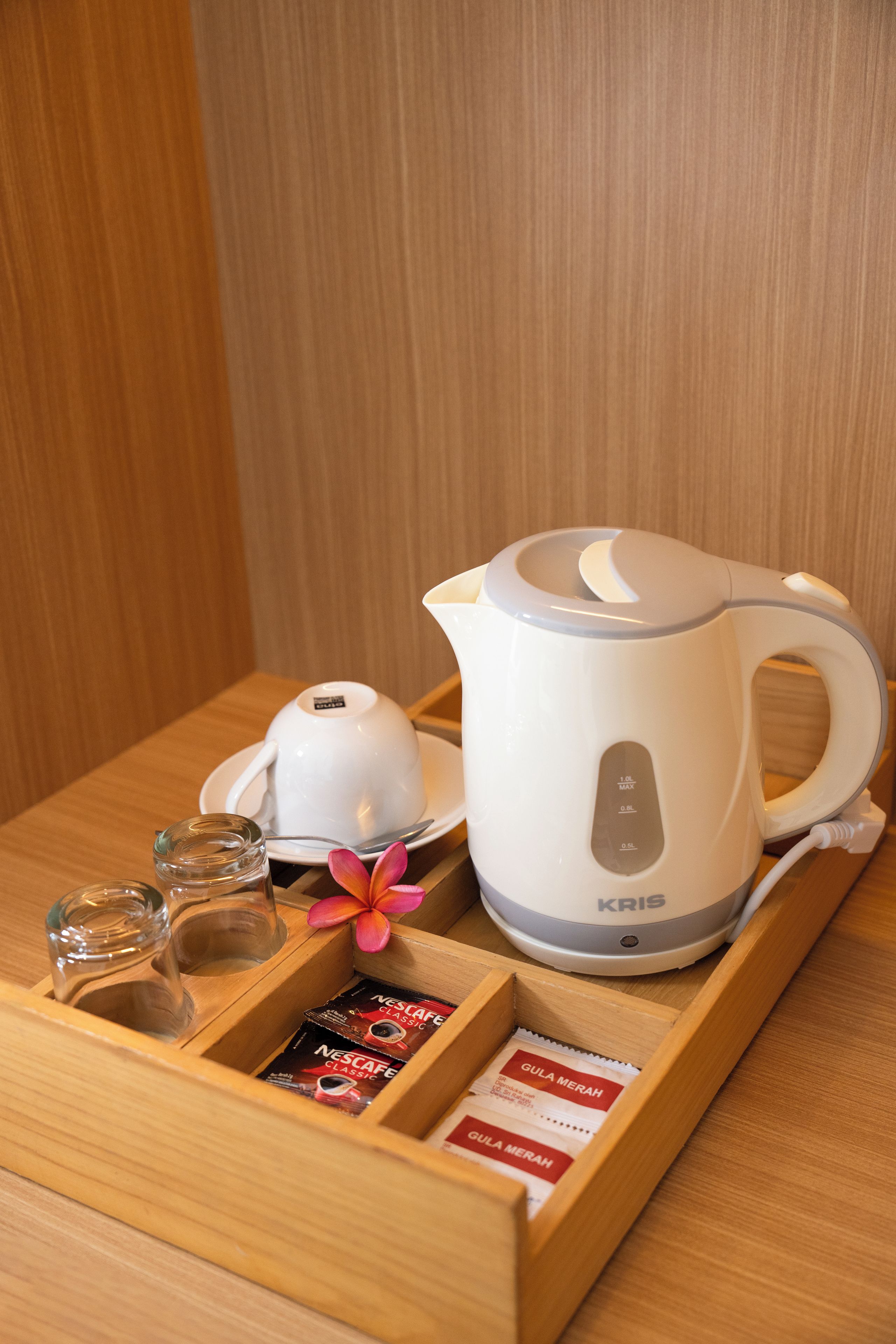 A coffee maker, a glass, a flower, and a tray with coffee pods.