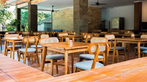 A restaurant with wooden tables and chairs, numbered seating, and a view of greenery outside. - Sandat Mas Uluwatu (Uluwatu)