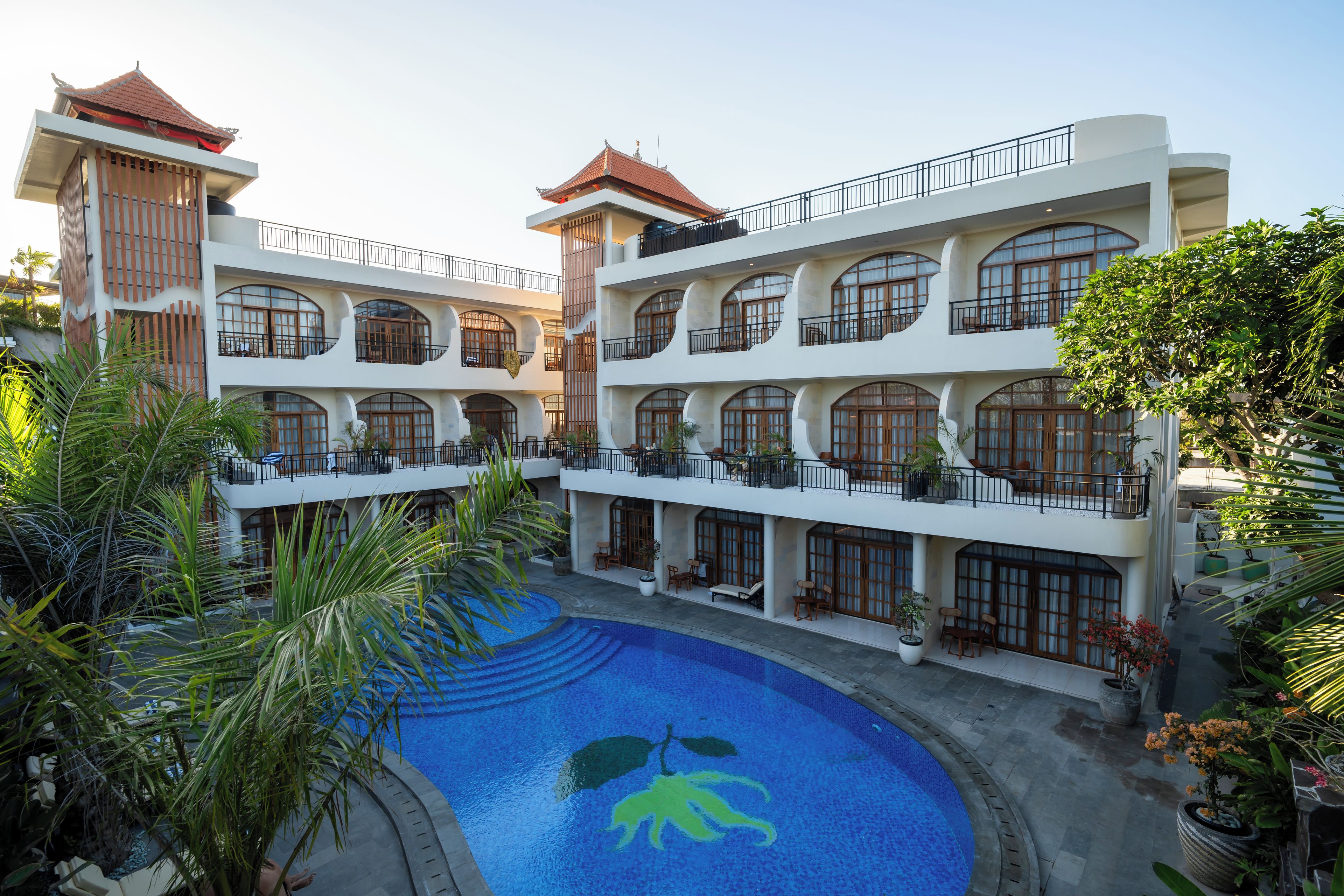 Un hotel de varios pisos con un patio central que incluye una piscina con un mural de delfines.