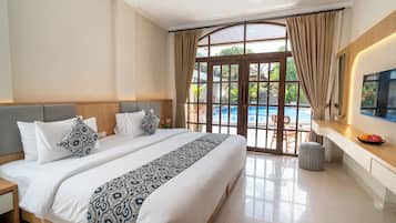 Habitación de hotel con una cama grande, un escritorio, un televisor y vistas a una piscina.