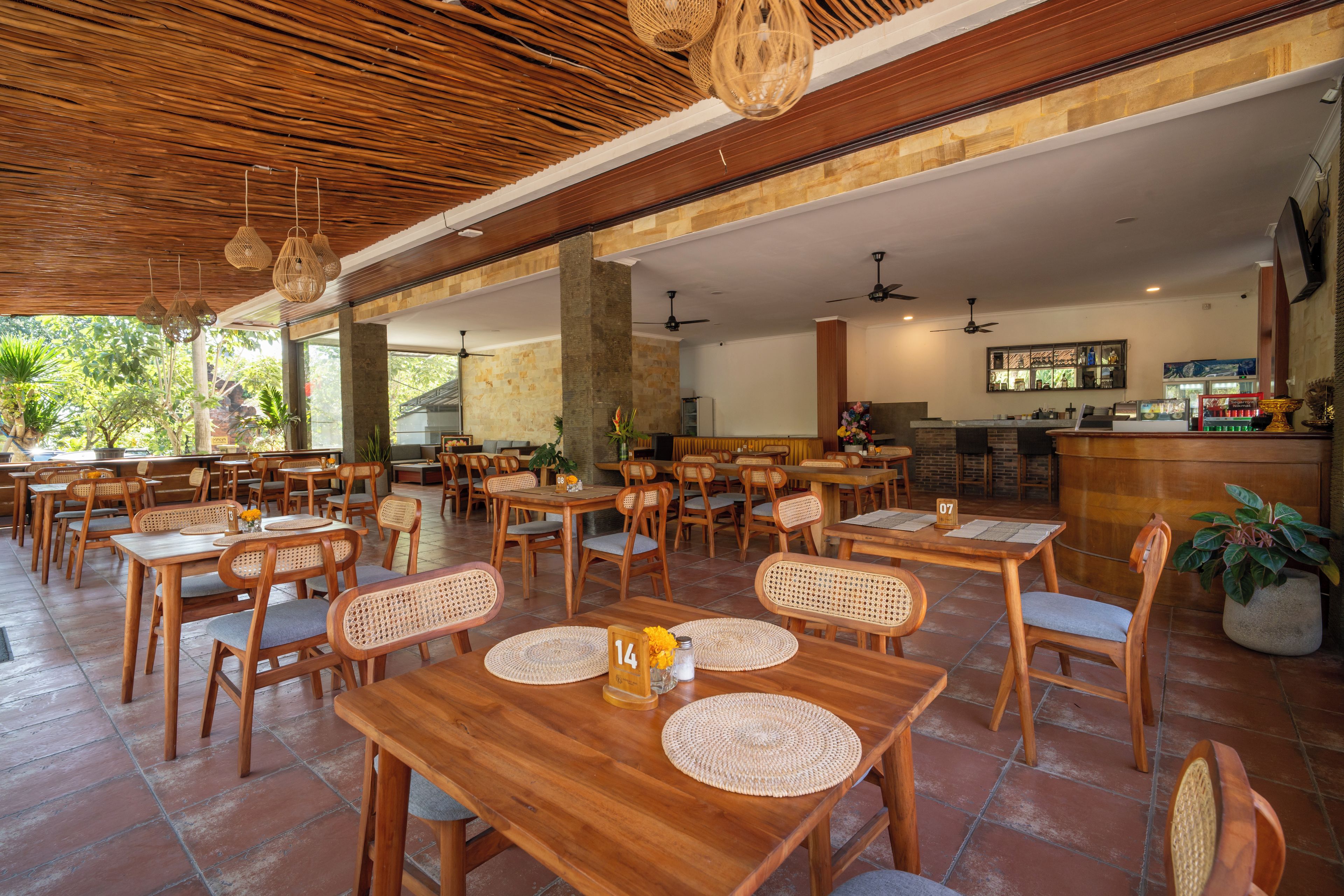 Un restaurante espacioso con mesas y sillas de madera, amplias ventanas y una zona de bar.
