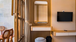 A modern bathroom with a wooden vanity, a mirror, a television, and a trash bin. - Sandat Mas Uluwatu (Uluwatu)