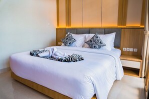 A hotel room with a bed, bedside table, and a wall-mounted light fixture.