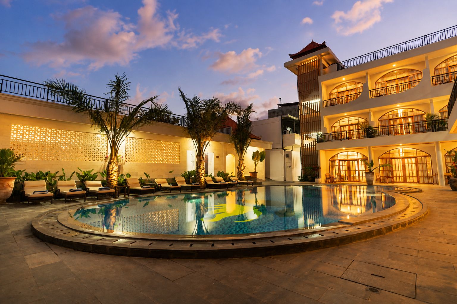 A hotel with a large outdoor pool, multiple balconies, and a well-lit facade.