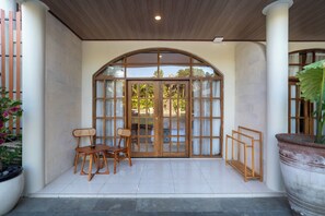 A covered patio area with a wooden bench, a table, and a potted plant. - Sandat Mas Uluwatu (Uluwatu)