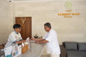 A reception desk with a wooden counter, a guestbook, and a sign indicating the hotel name 'SANDAT MAS Uluwatu'. - Sandat Mas Uluwatu (Uluwatu)
