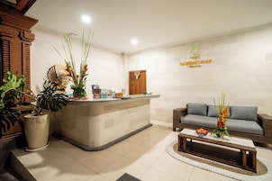 Un área de recepción con mostrador, un sofá y plantas en macetas.