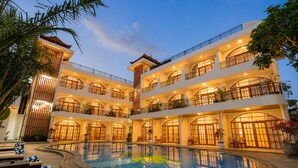A multi-story hotel with a central pool, balconies, and outdoor seating areas.