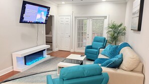 Ein Wohnzimmer mit Flachbildfernseher, Kamin, Sofa und Couchtisch.