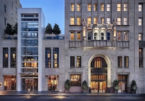 A hotel with a modern glass facade, a classic arched entrance, and a decorative facade with intricate detailing.