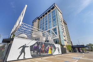 A modern building with a glass facade, a large mural on the side, and a parking lot with handicapped spaces.