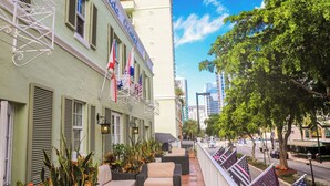 A hotel with outdoor seating, flags, and a view of the street.