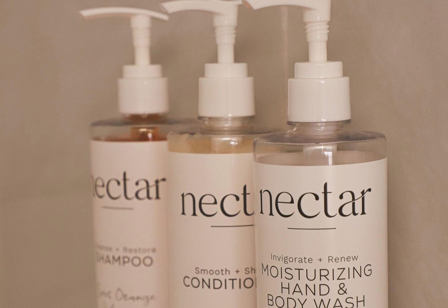 Três embalagens de produtos Nectar: shampoo, condicionador e creme hidratante para as mãos e corpo.