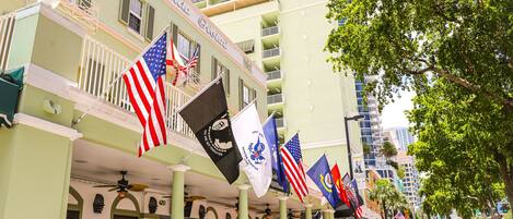 Un hôtel arborant plusieurs drapeaux, dont le drapeau américain, et doté d’un balcon avec une balustrade.