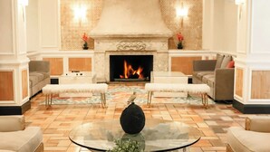 A spacious lobby with a fireplace, two sofas, a round table with a decorative vase, and a patterned rug. - Jr Riverview Balc | Riverside Hotel | Riverview Balcony, Las Olas Blvd,New River (Broward County)
