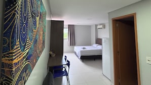 A room with a bed, a desk, a chair, a wall art piece, and a door. - Residencial Macambira (Campina Grande)