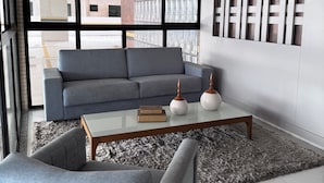 A modern living room with a grey sofa, a coffee table, and a grey armchair. - Residencial Macambira (Campina Grande)