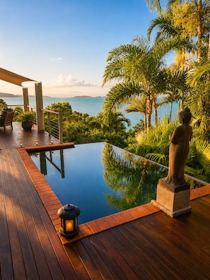 A wooden deck with a clear view of the sea, a statue, and a small pool.