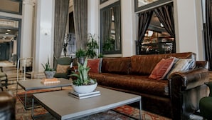 Un salon avec un canapé en cuir marron, une table basse ornée d’une plante et un tapis à motifs.