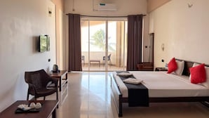 Habitació d'hotel amb llit, escriptori, cadira, televisió i una porta corredissa que dona a un balcó.