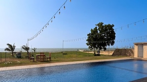 Piscina amb vistes al mar, llums penjades i mobiliari exterior.