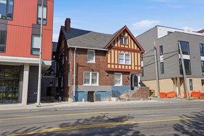 A street view with a mix of residential buildings, including a two-story house with a gabled roof and a modern building with a flat roof. - Four Tops Suite  Renovated 2BR/2BA Midtown (Detroit)