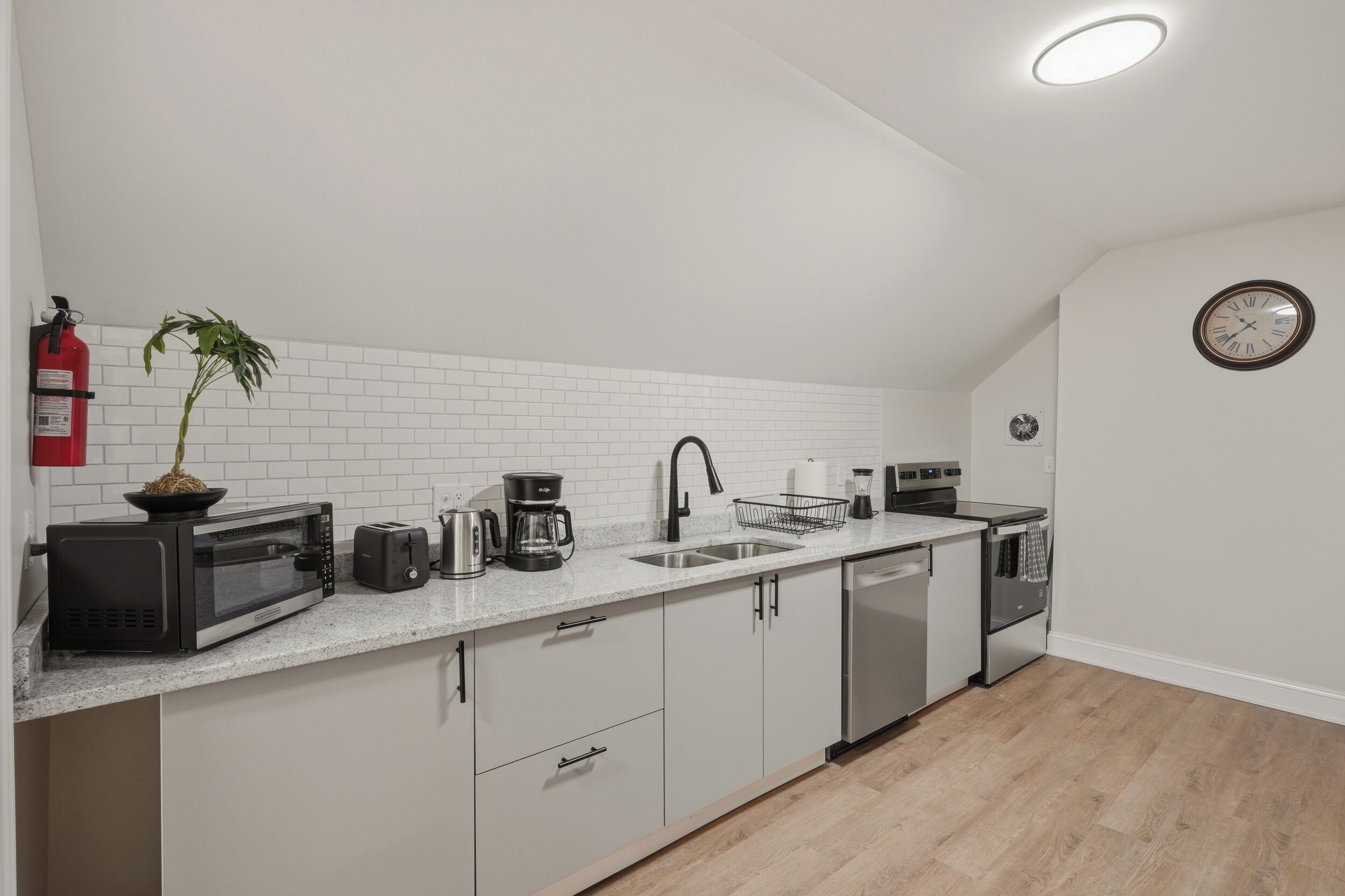 A modern kitchen with white subway tiles, stainless steel appliances, and a potted plant.