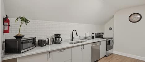 A modern kitchen with white subway tiles, stainless steel appliances, and a potted plant.