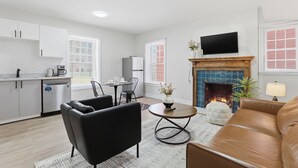 Un salon moderne doté d’une cheminée, d’un téléviseur à écran plat et d’un coin repas avec une table et des chaises.