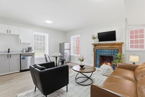 Ein modernes Wohnzimmer mit Kamin, Flachbildfernseher und Essbereich mit Tisch und Stühlen.