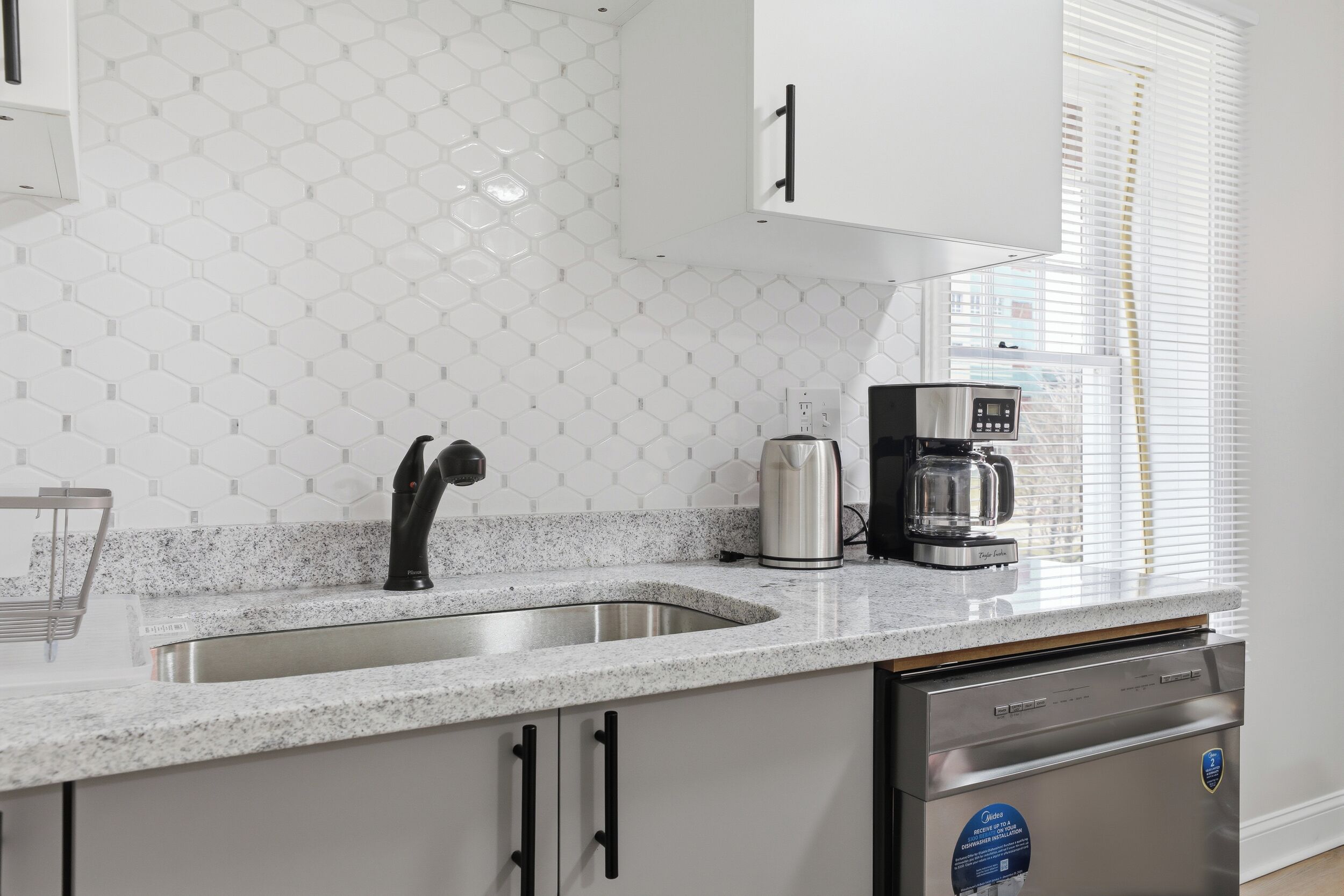 A kitchen with a stainless steel sink, a coffee maker, and a dishwasher.